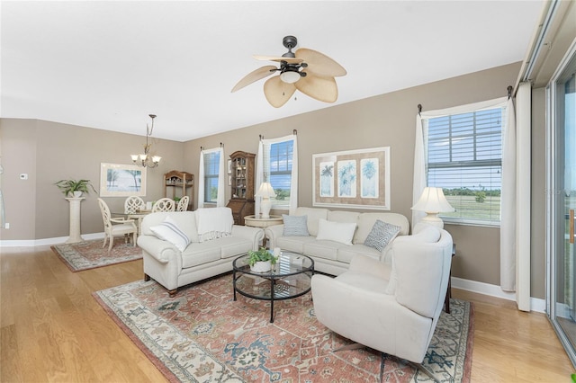 living room with ceiling fan with notable chandelier and light hardwood / wood-style floors