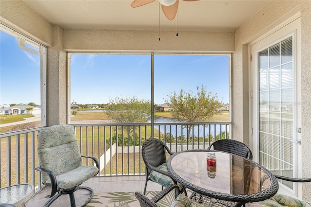 sunroom featuring ceiling fan and a water view