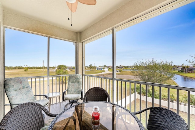 sunroom with a water view and ceiling fan