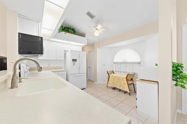 kitchen featuring sink, ceiling fan, white fridge with ice dispenser, light tile patterned flooring, and white cabinetry