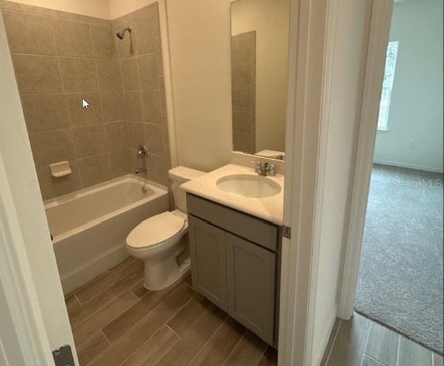 full bathroom featuring tiled shower / bath combo, toilet, and vanity