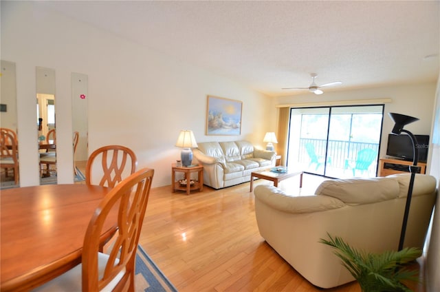 living room featuring ceiling fan, light hardwood / wood-style flooring, and a textured ceiling