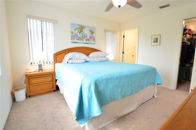 bedroom with ceiling fan, a spacious closet, light carpet, and a closet