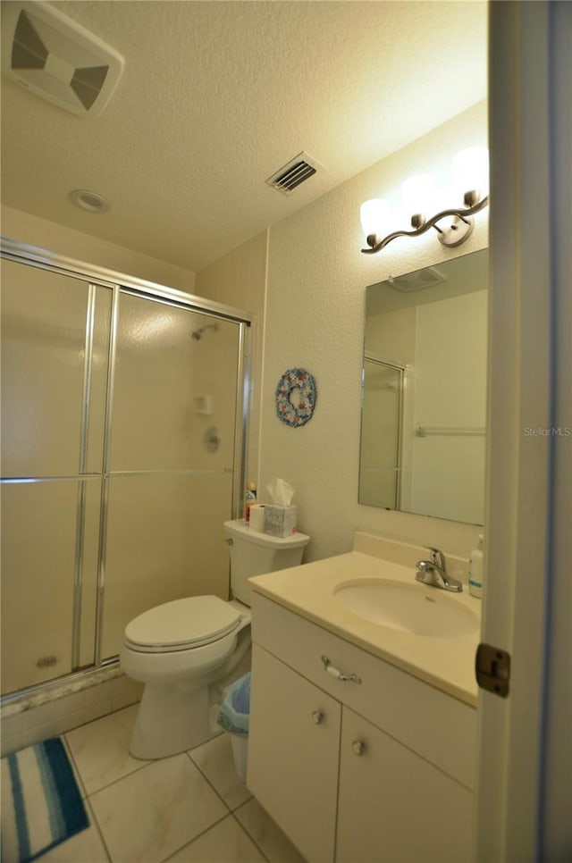 bathroom featuring tile patterned floors, a textured ceiling, toilet, vanity, and a shower with shower door