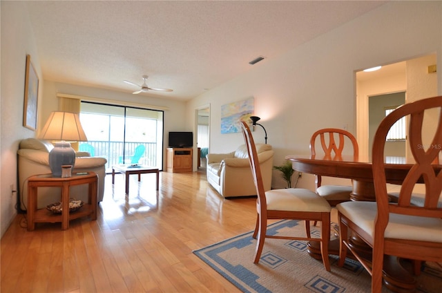 living area featuring ceiling fan, light hardwood / wood-style floors, and a textured ceiling