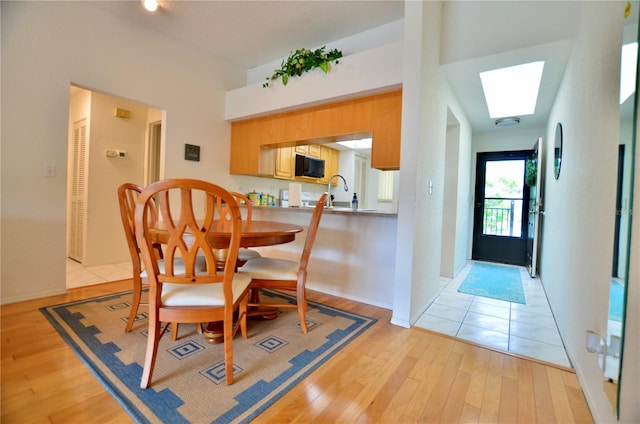 dining room featuring a skylight, light hardwood / wood-style flooring, and sink