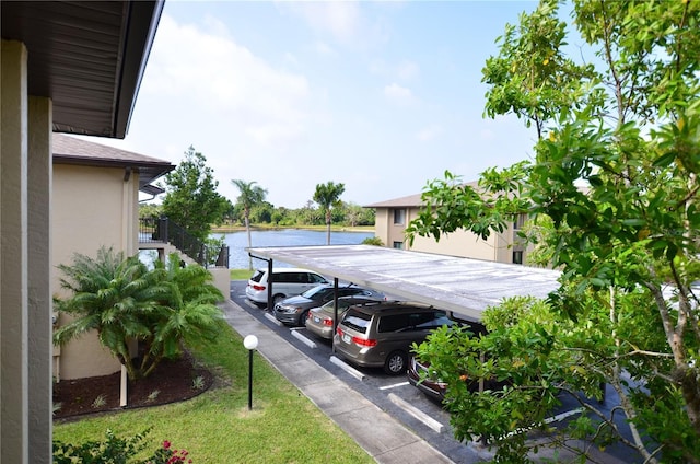 view of parking with a carport and a water view