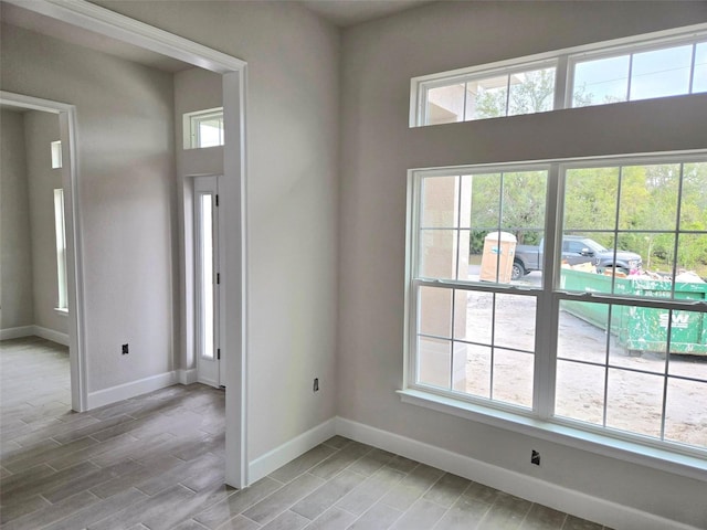 spare room with light wood-style flooring, baseboards, and a wealth of natural light