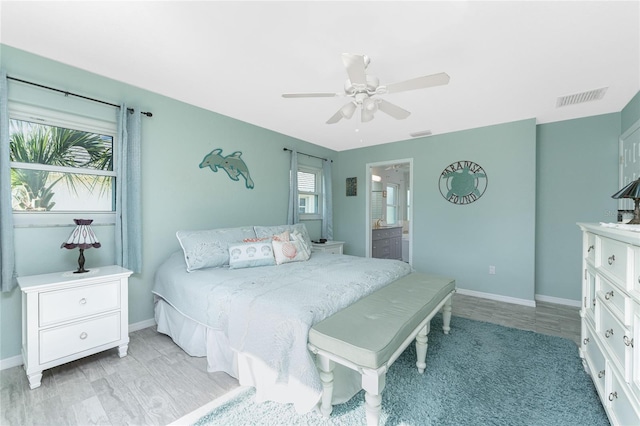 bedroom with multiple windows, light hardwood / wood-style floors, ensuite bath, and ceiling fan