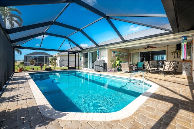 view of pool featuring a patio area, ceiling fan, glass enclosure, and grilling area