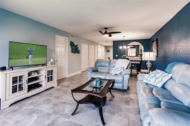 living room with ceiling fan with notable chandelier