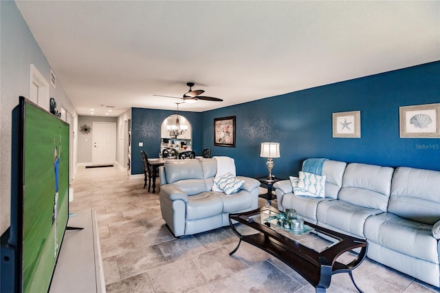 living room with ceiling fan with notable chandelier