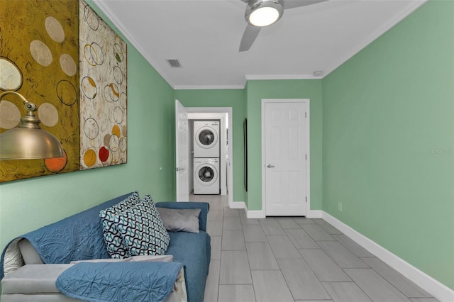 sitting room with stacked washer / dryer, crown molding, and ceiling fan