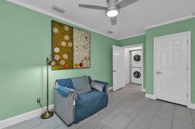 living area with light tile patterned flooring, stacked washer / dryer, crown molding, and ceiling fan