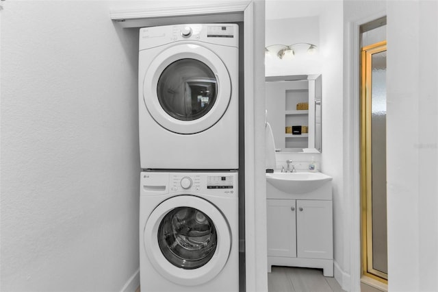 clothes washing area featuring sink and stacked washer and clothes dryer