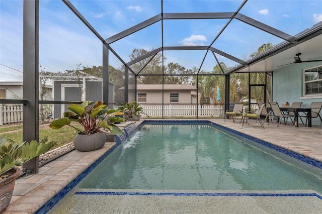 view of pool with pool water feature, glass enclosure, ceiling fan, and a patio