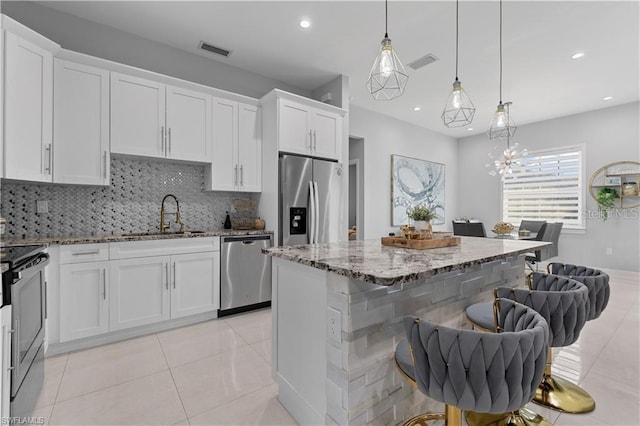 kitchen with white cabinets, sink, a breakfast bar area, and appliances with stainless steel finishes