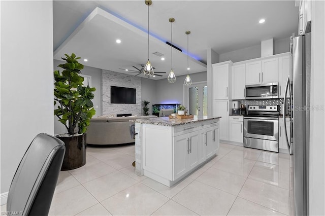 kitchen featuring a kitchen island, light stone counters, white cabinetry, and appliances with stainless steel finishes