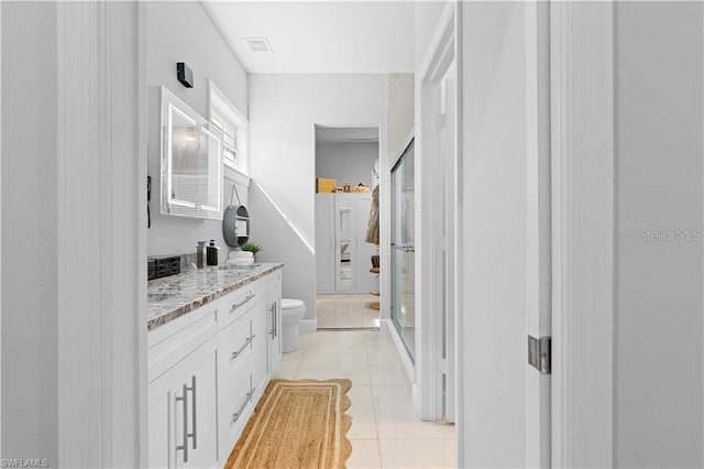 bathroom featuring tile patterned flooring, vanity, toilet, and a shower with shower door