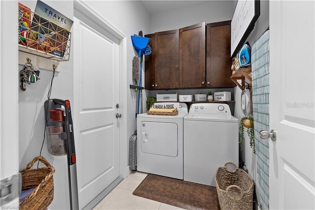 laundry room with washer and clothes dryer, cabinets, and light tile patterned floors