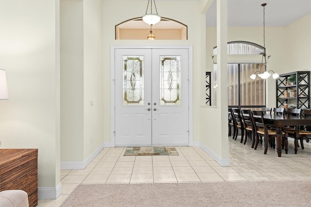 entryway with a chandelier, light tile patterned floors, and french doors