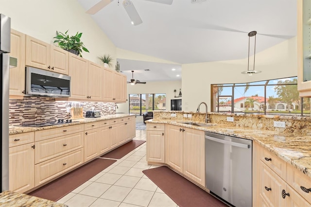 kitchen featuring light stone countertops, sink, hanging light fixtures, lofted ceiling, and appliances with stainless steel finishes