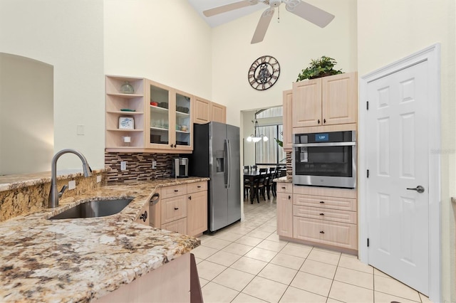 kitchen featuring light brown cabinets, stainless steel appliances, light stone counters, and sink