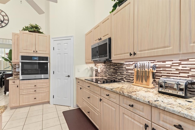 kitchen featuring light stone countertops, light brown cabinets, stainless steel appliances, decorative backsplash, and light tile patterned flooring