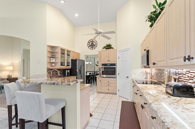 kitchen with ceiling fan, stainless steel appliances, backsplash, a kitchen bar, and light tile patterned flooring