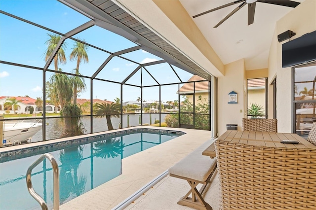 view of swimming pool with glass enclosure, ceiling fan, a patio area, and a water view