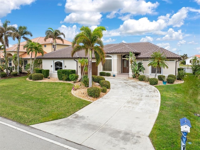 mediterranean / spanish-style house featuring driveway, a tile roof, a front lawn, and stucco siding