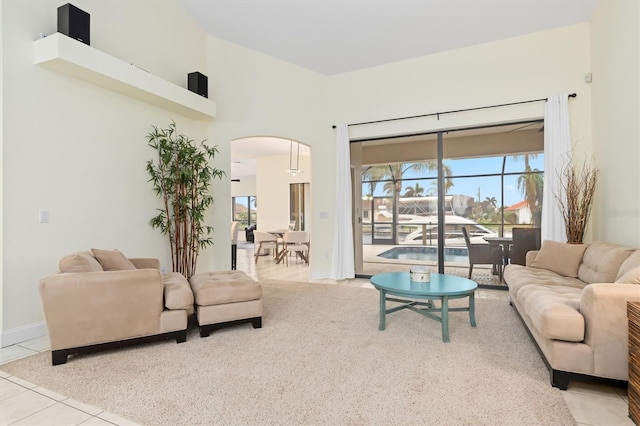 living room featuring tile patterned flooring, arched walkways, and baseboards