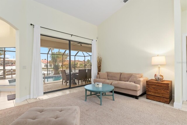 living room with arched walkways, a sunroom, tile patterned floors, vaulted ceiling, and carpet flooring