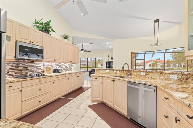 kitchen with light tile patterned floors, tasteful backsplash, appliances with stainless steel finishes, vaulted ceiling, and a sink