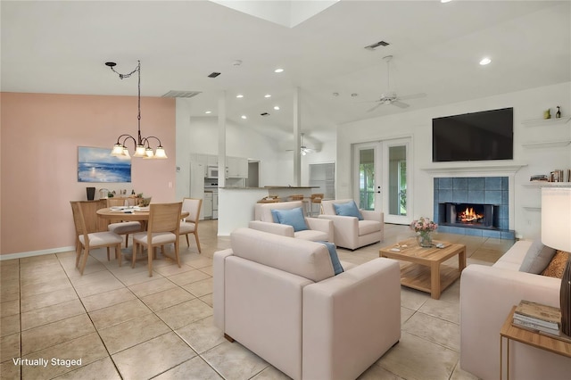 tiled living room with a fireplace, ceiling fan with notable chandelier, and vaulted ceiling