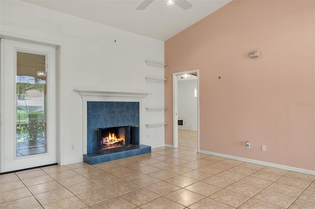 unfurnished living room with light tile patterned floors, high vaulted ceiling, ceiling fan, and a tiled fireplace