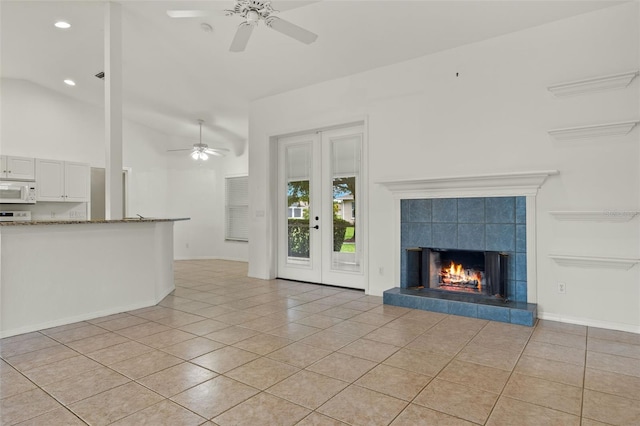 unfurnished living room with ceiling fan, light tile patterned flooring, a fireplace, and high vaulted ceiling