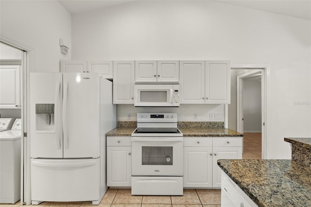 kitchen featuring washer and dryer, white cabinetry, dark stone countertops, and white appliances