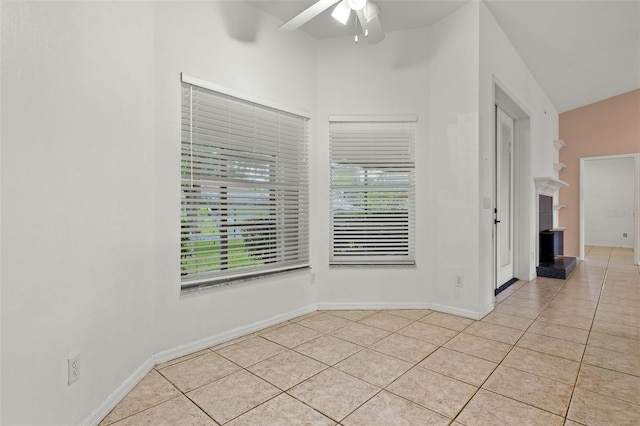 unfurnished room featuring ceiling fan, light tile patterned floors, and vaulted ceiling