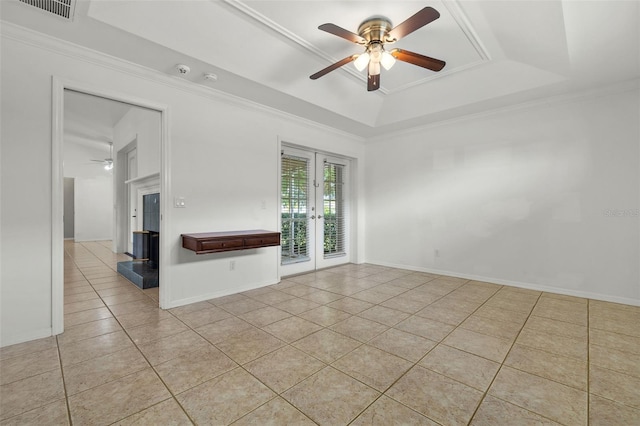 unfurnished living room with french doors, ornamental molding, a raised ceiling, ceiling fan, and light tile patterned floors