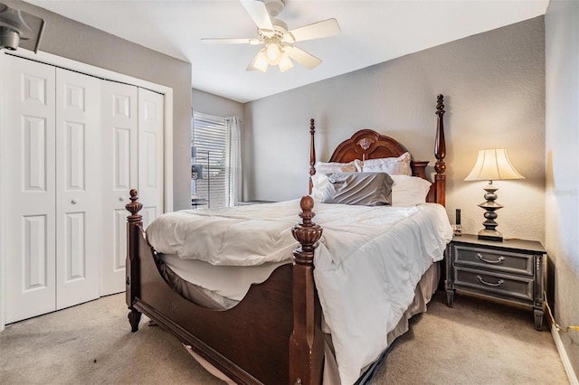 bedroom with ceiling fan, light colored carpet, and a closet