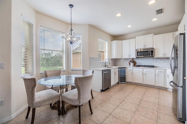 kitchen with pendant lighting, wine cooler, light tile patterned flooring, white cabinetry, and stainless steel appliances