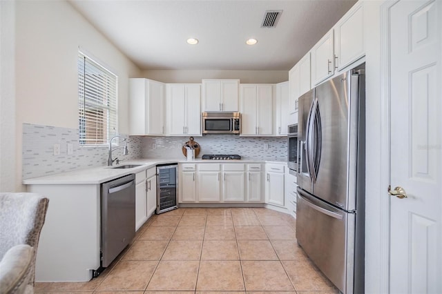 kitchen with sink, stainless steel appliances, light tile patterned floors, wine cooler, and white cabinets