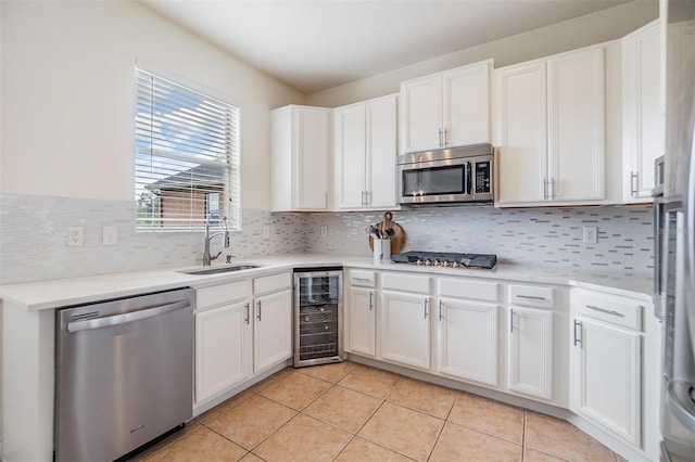 kitchen featuring white cabinets, wine cooler, light tile patterned floors, appliances with stainless steel finishes, and tasteful backsplash