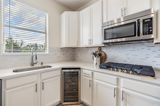 kitchen with white cabinetry, sink, beverage cooler, stainless steel appliances, and tasteful backsplash