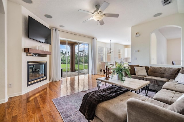 living room featuring ceiling fan with notable chandelier, wood-type flooring, and sink