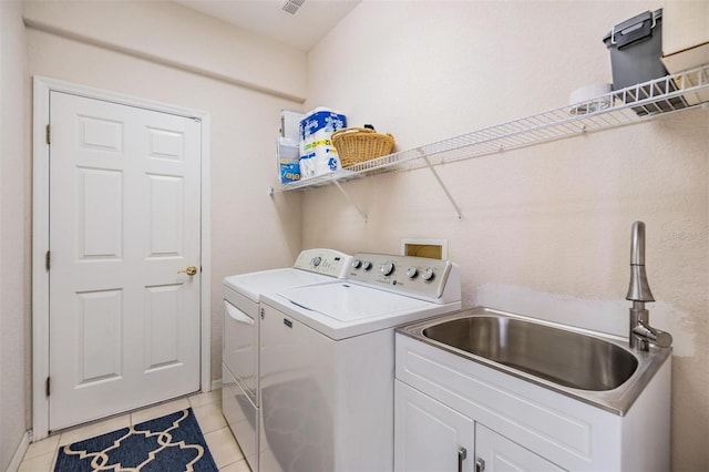 laundry area featuring washer and clothes dryer, light tile patterned floors, and sink