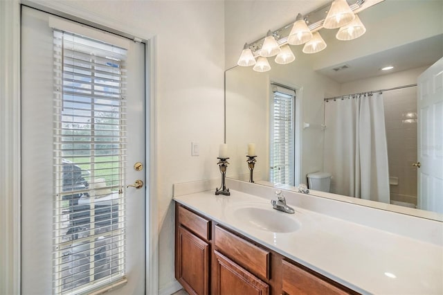 bathroom featuring a shower with shower curtain, vanity, a healthy amount of sunlight, and toilet