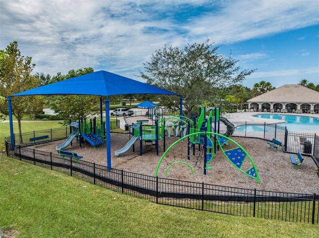 view of jungle gym featuring a lawn and a community pool