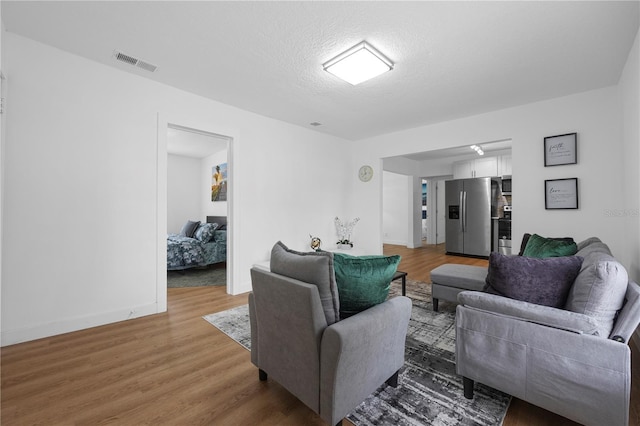 living room featuring visible vents, light wood-style flooring, attic access, and baseboards